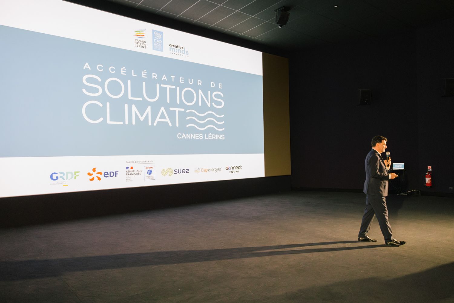 Speaker presents on stage at Solutions Climate conference with branded backdrop.