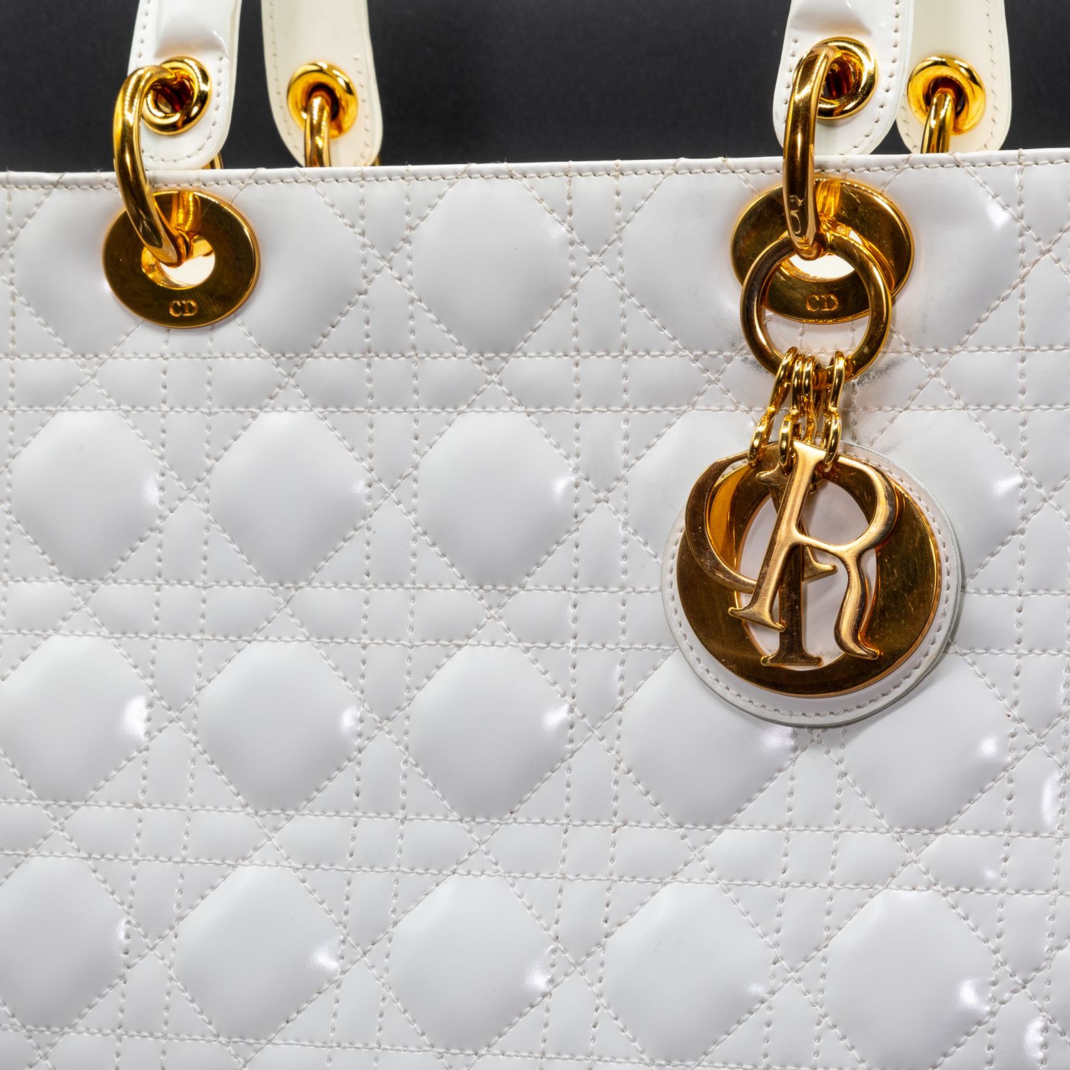 Detail of white quilted leather with gold hardware and Dior charm.