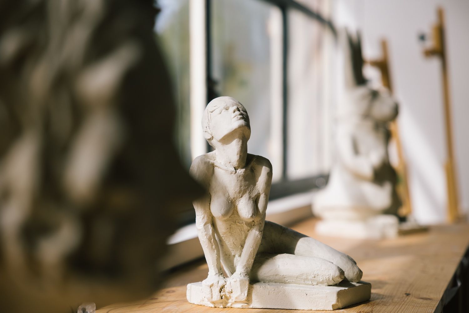 Small decorative sculpture of a seated figure in white material.