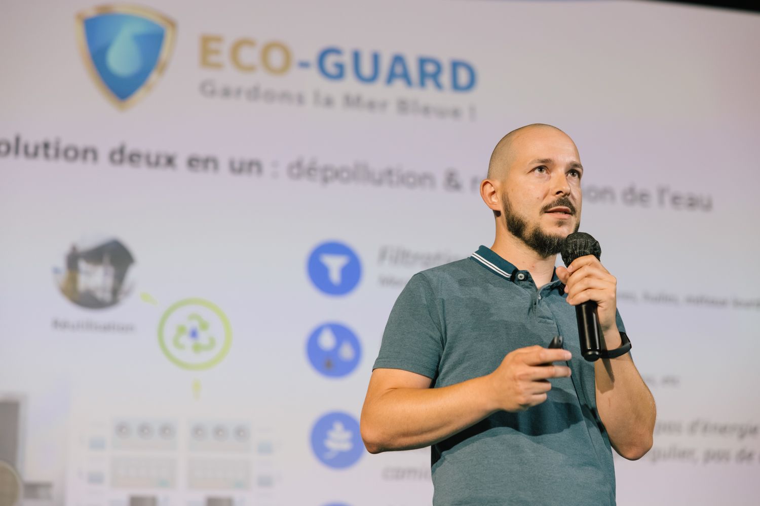 A person gives a presentation in front of a large screen displaying eco-friendly technology information.