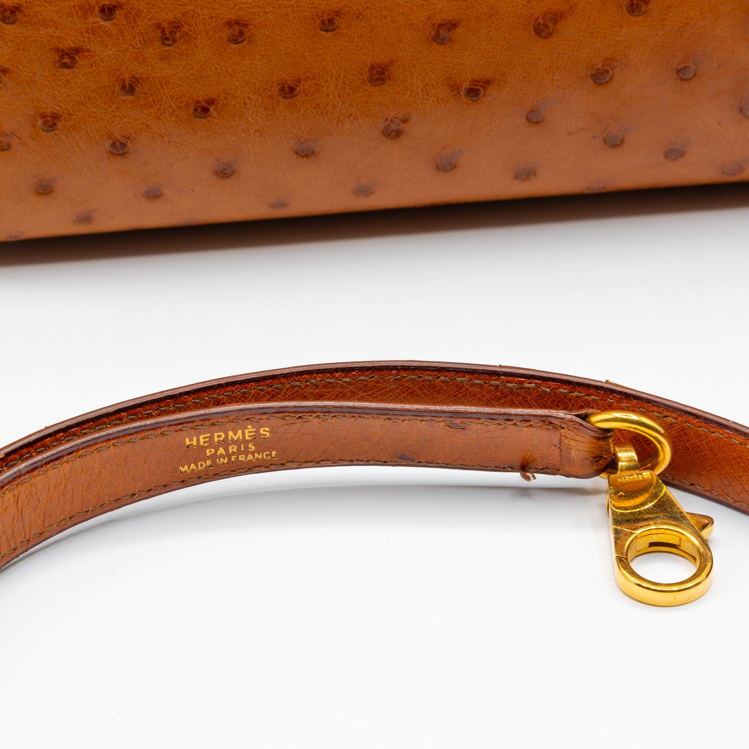 Close-up detail of brown leather with gold hardware showing Hermes branding.