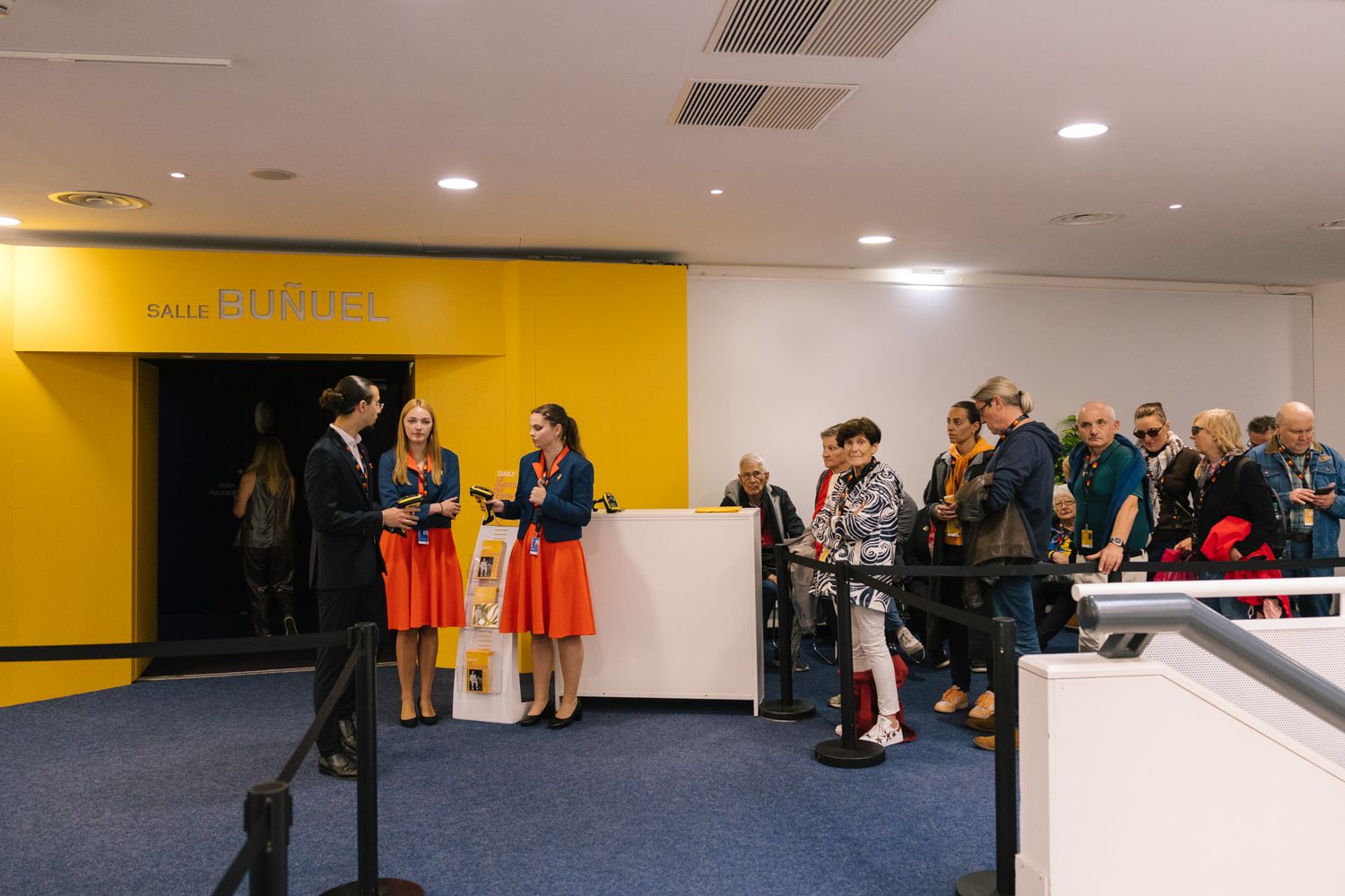 People networking in a yellow-walled hallway during a film festival event.