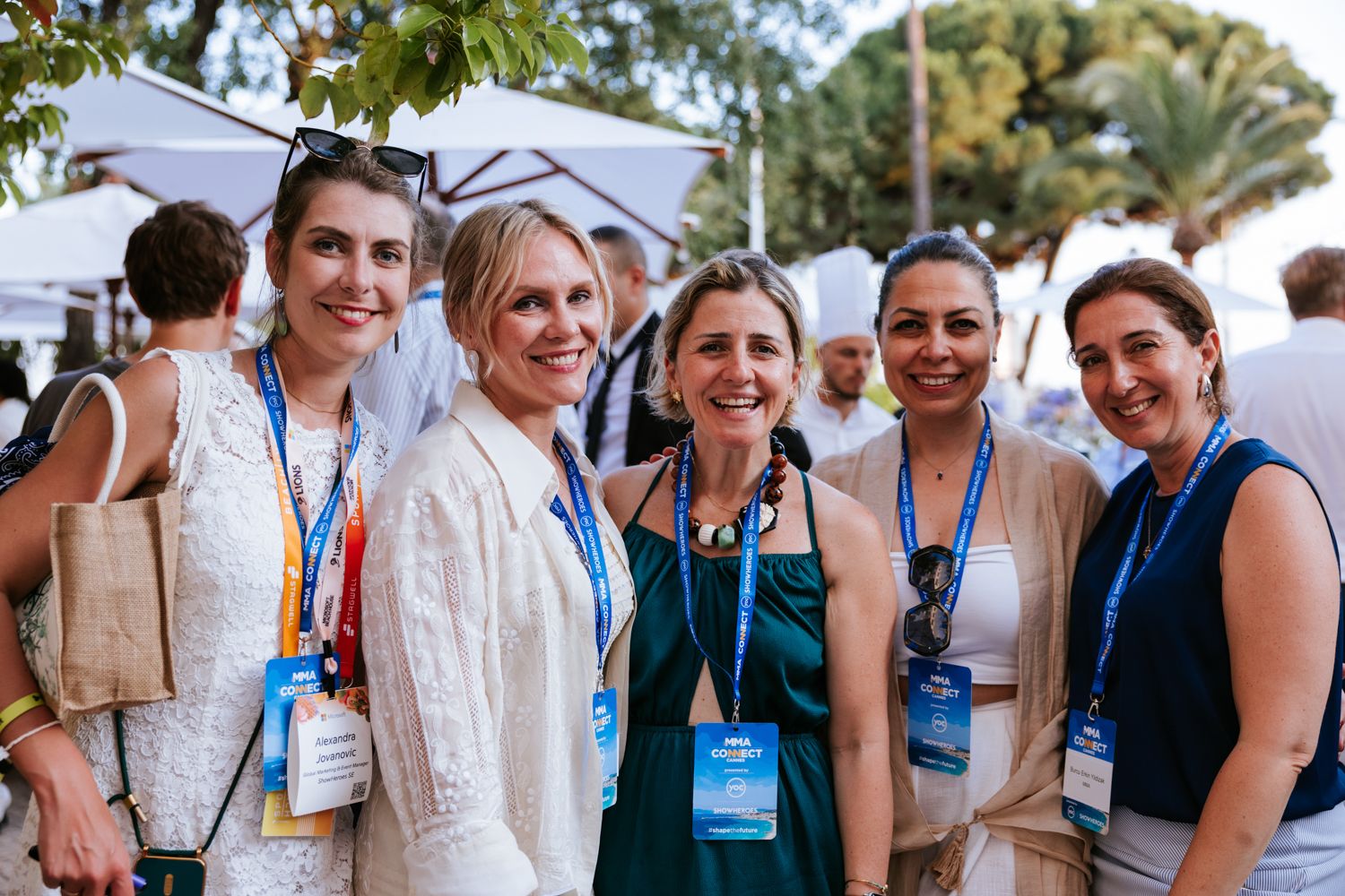 A group of conference attendees wearing name badges gather outdoors for a networking event.