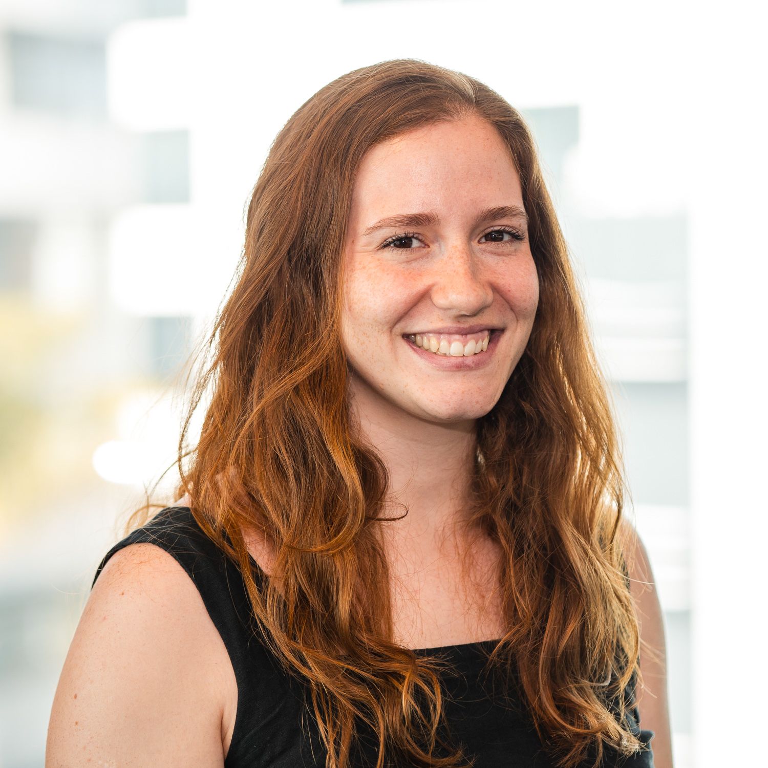 Professional headshot of a person wearing black against an office background.