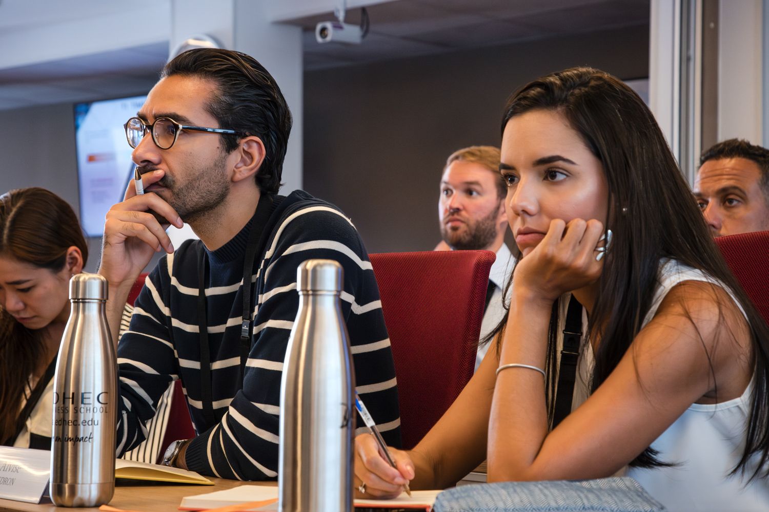 Students engaged in discussion during a classroom session with reusable water bottles on their desk.
