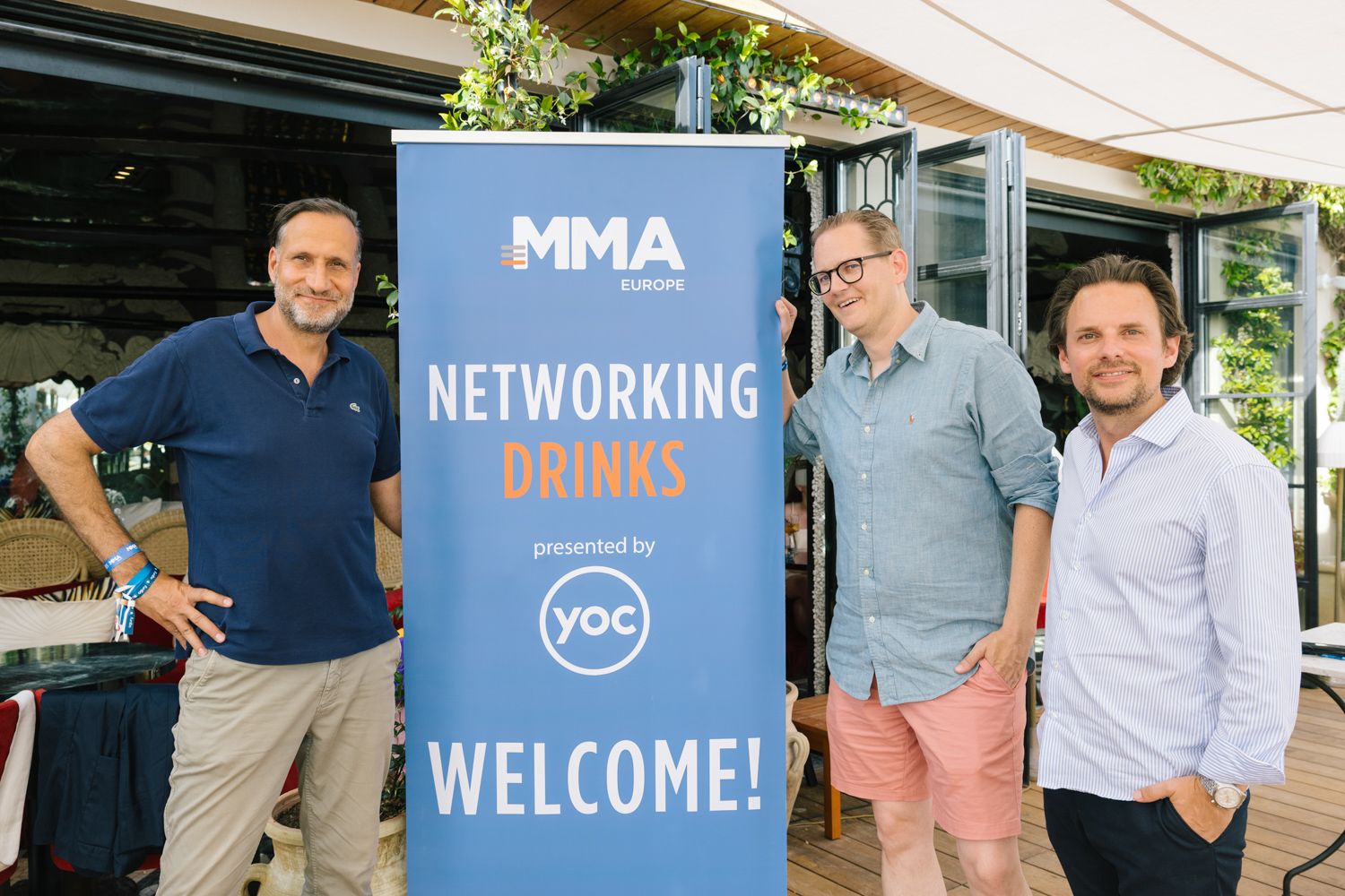 Networking event with blue MMA banner and YOC branding displayed at an outdoor venue.