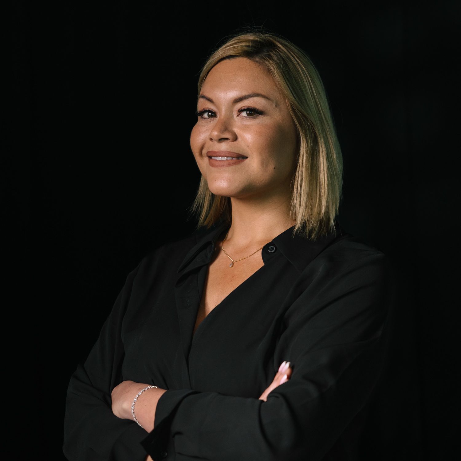 Professional portrait of a person in business attire against a dark background.