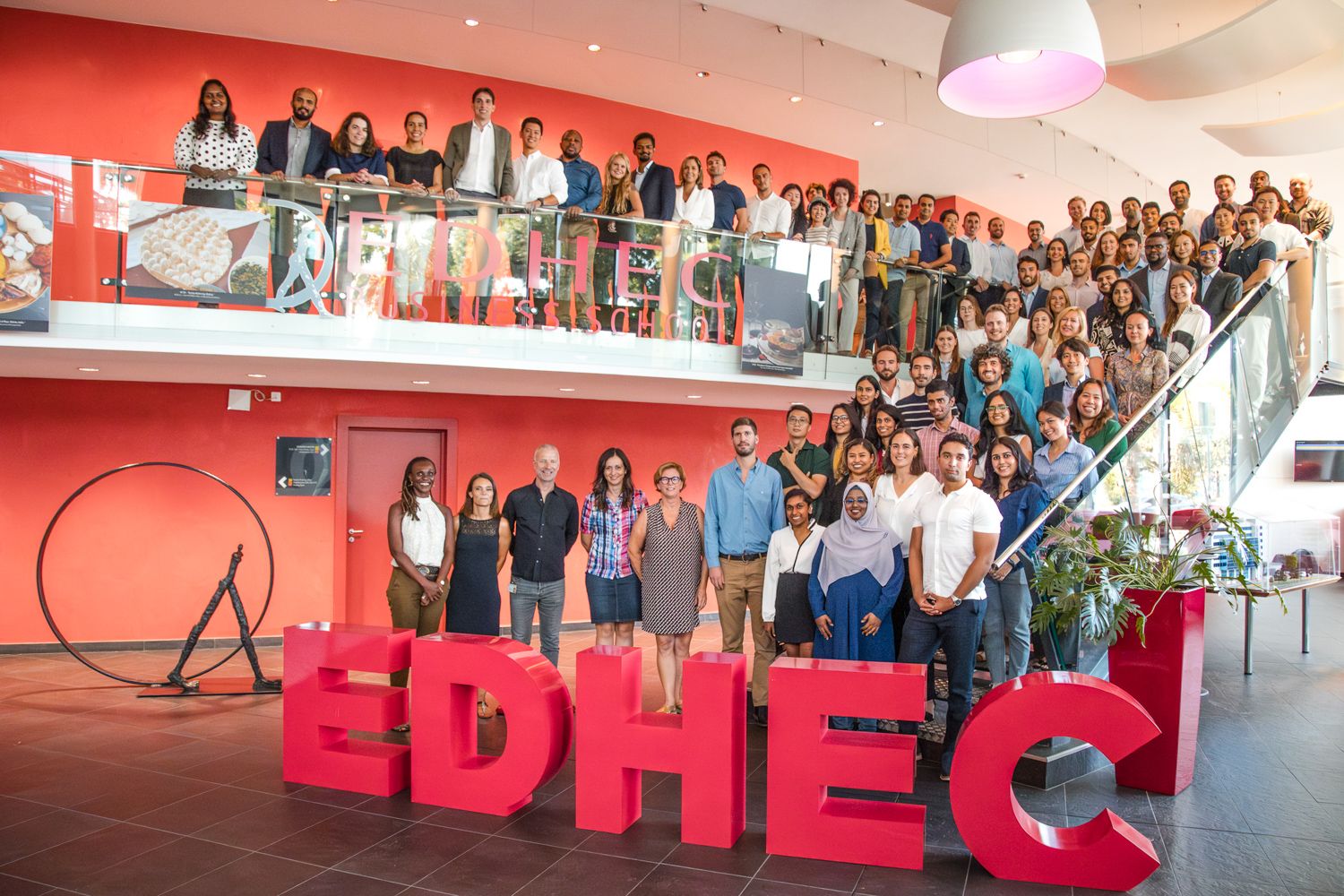 Large group of students gathered on stairs with EDHEC signage for a group photo.