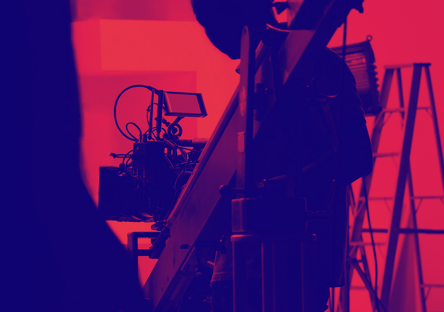 Silhouette of film production equipment against red background on set.