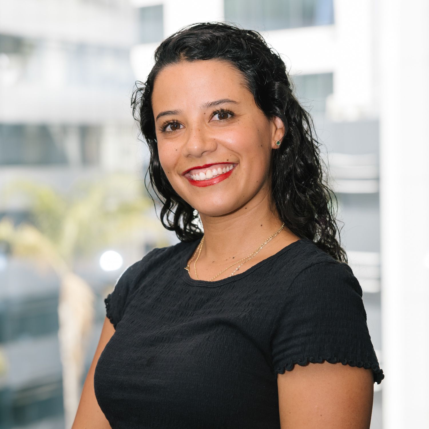 Professional in black top against office window background.