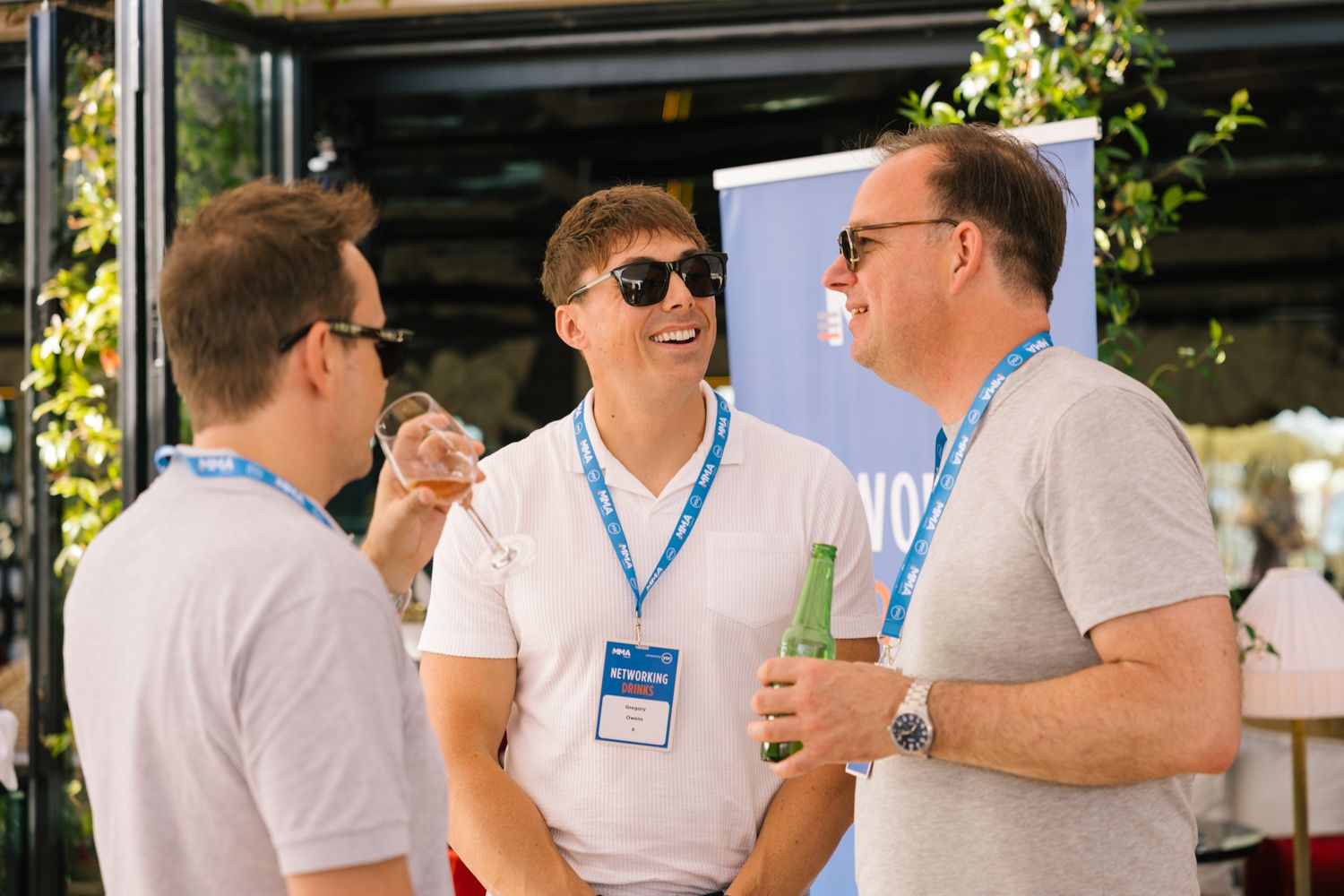 Conference attendees wearing lanyards engage in informal discussion outdoors.