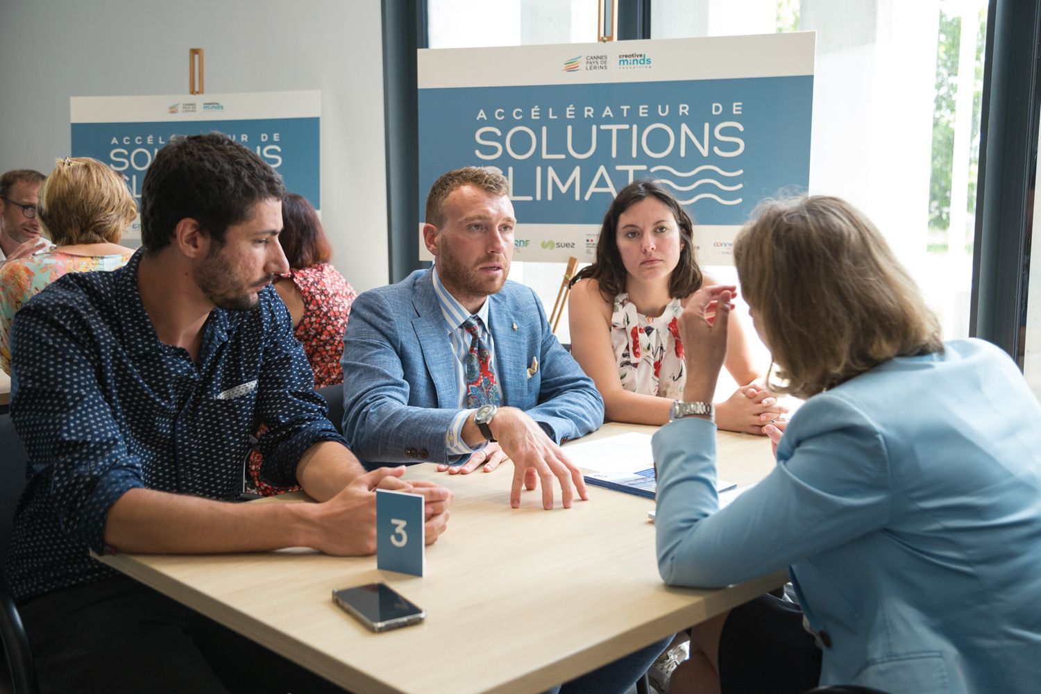 Business professionals having a meeting around a table with Solutions signage in background.
