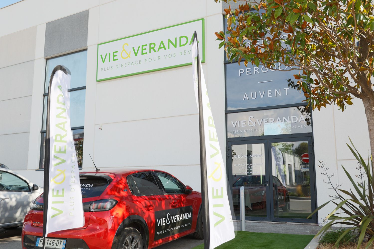 Exterior view of Vie Veranda showroom entrance with red car and promotional signage.