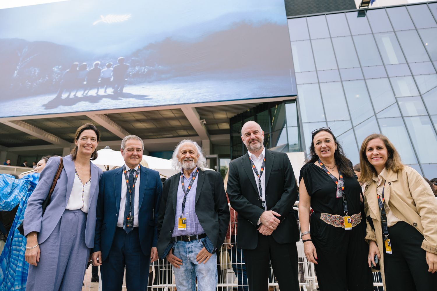 Group of festival delegates pose together outside the Cannes venue entrance.