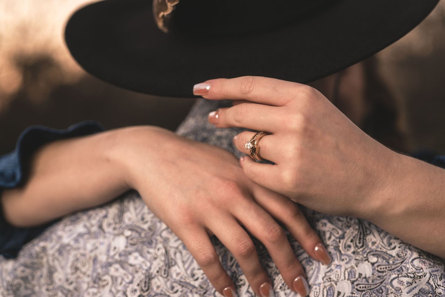 Close-up of hands showing an engagement ring with intricate lace and western details.
