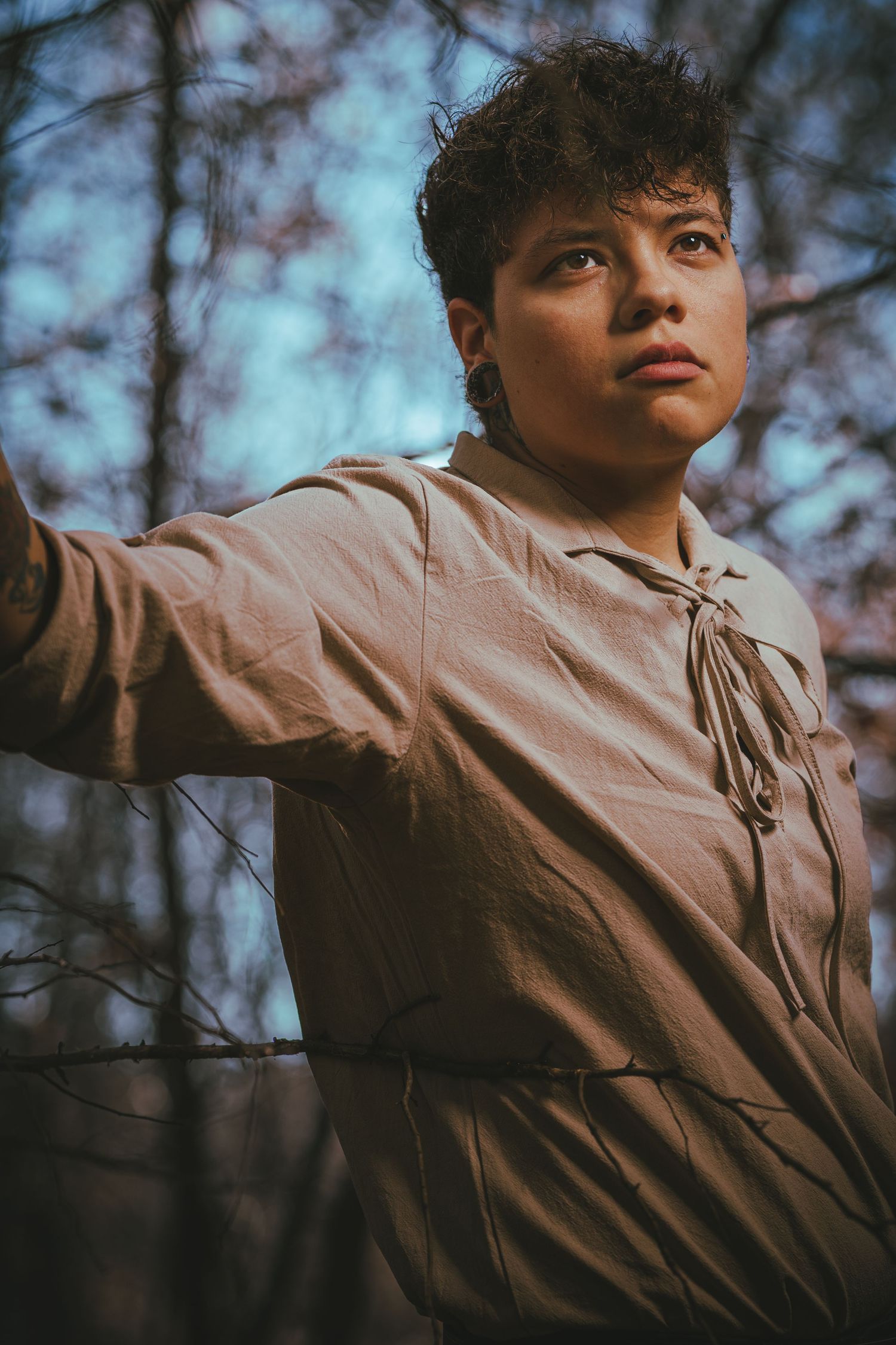 Dramatic upward angle portrait with sky and trees in background.