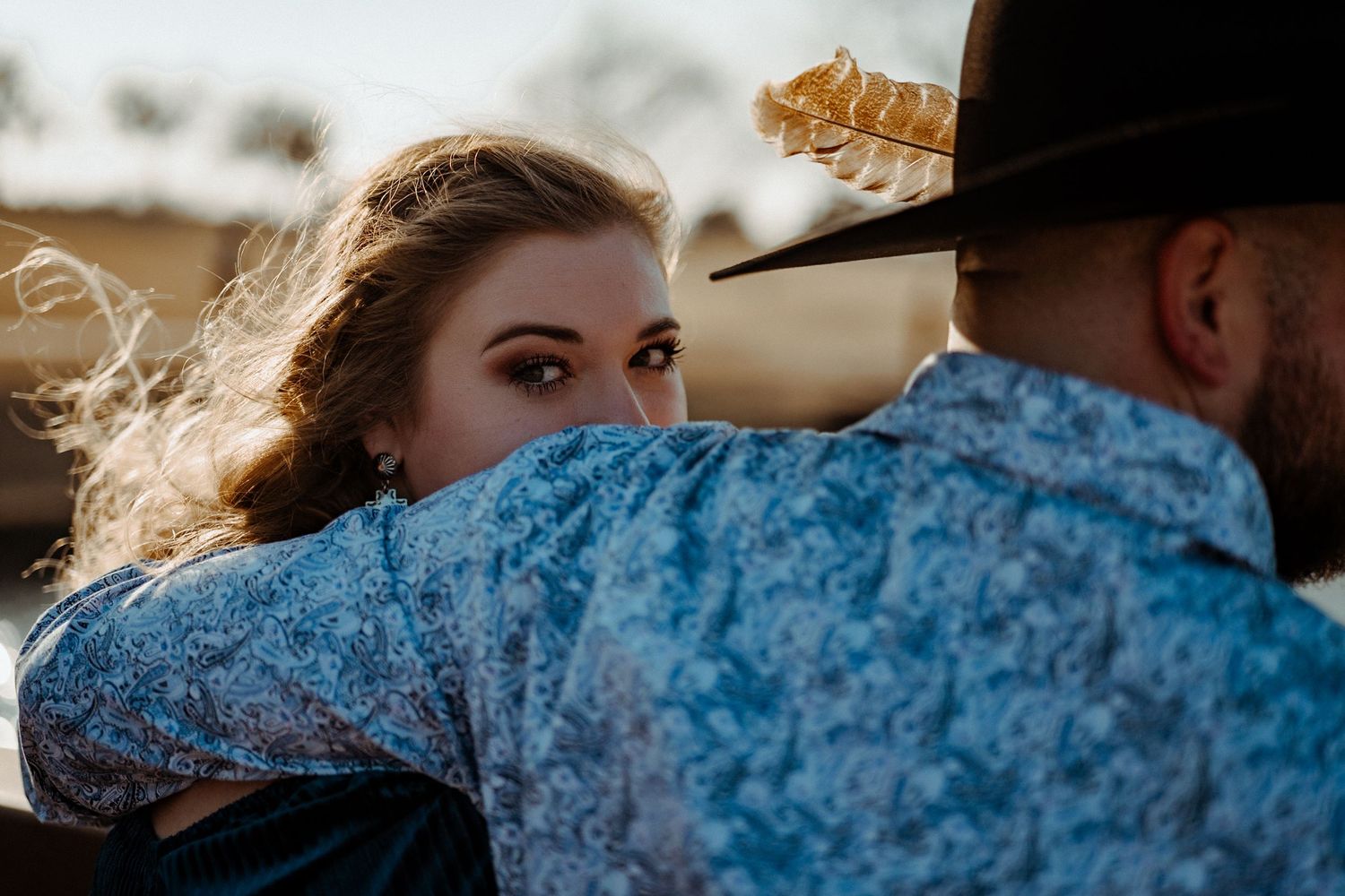 A romantic close-up shot showing western-styled clothing and a cowboy hat against a sunset backdrop.
