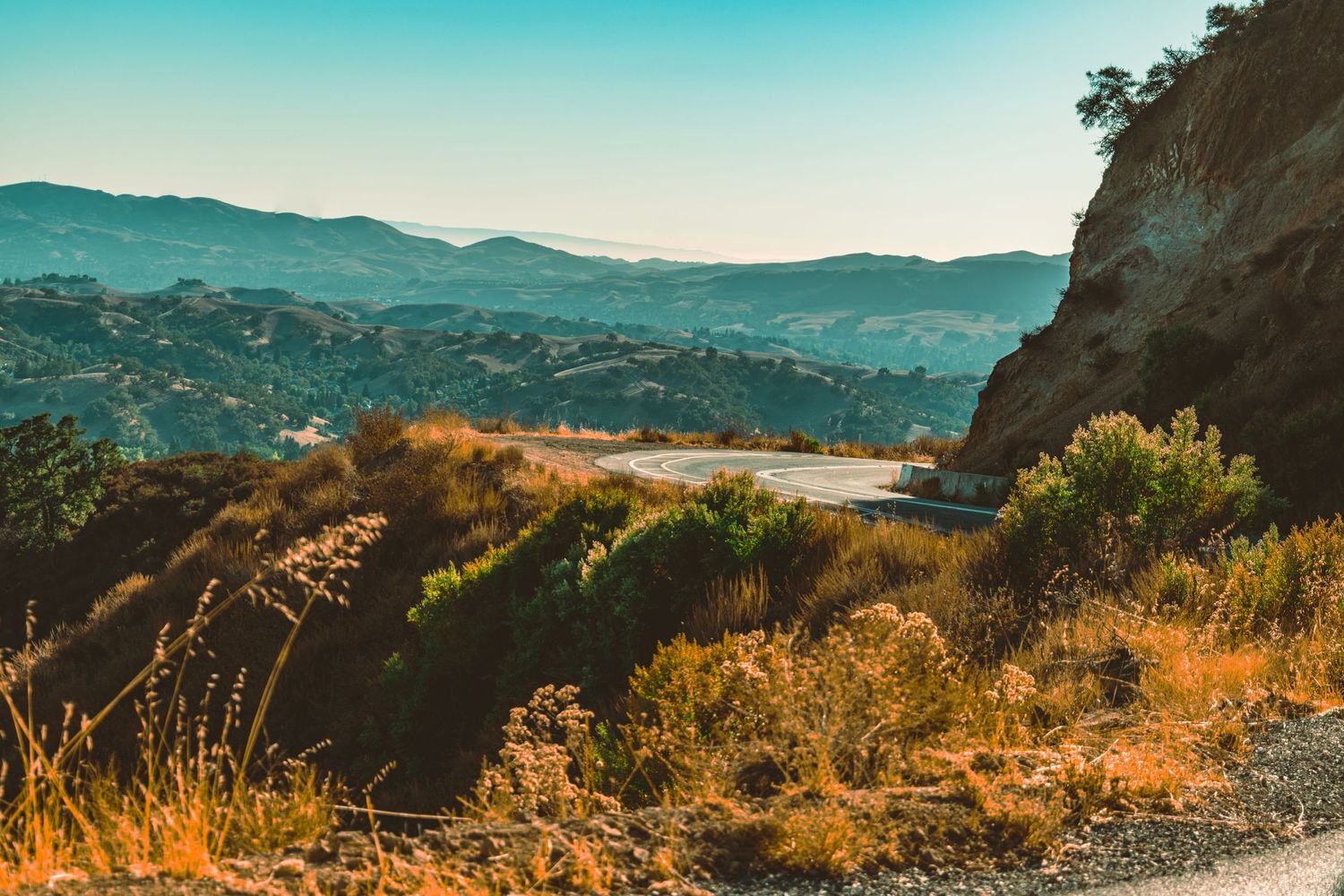 Scenic mountain landscape with golden brush and turquoise sky at sunset.