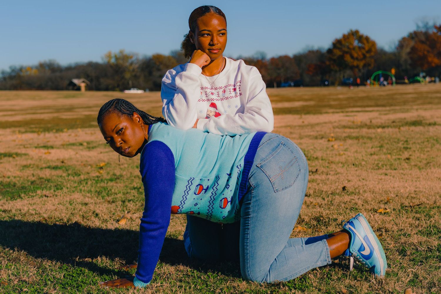 Two people in casual wear playing and posing in an open field.