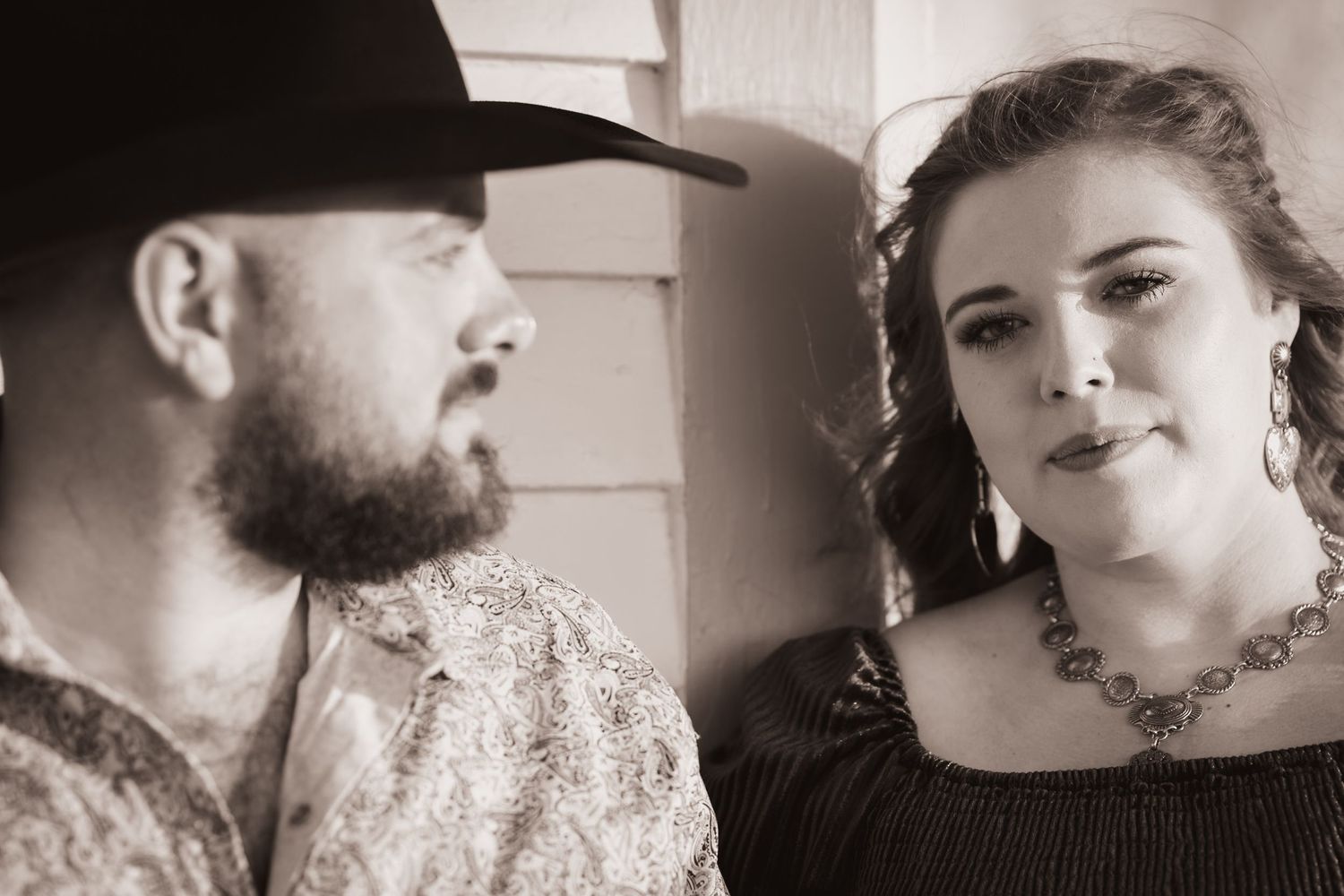 A vintage-style black and white portrait of a couple in western-inspired formal wear.