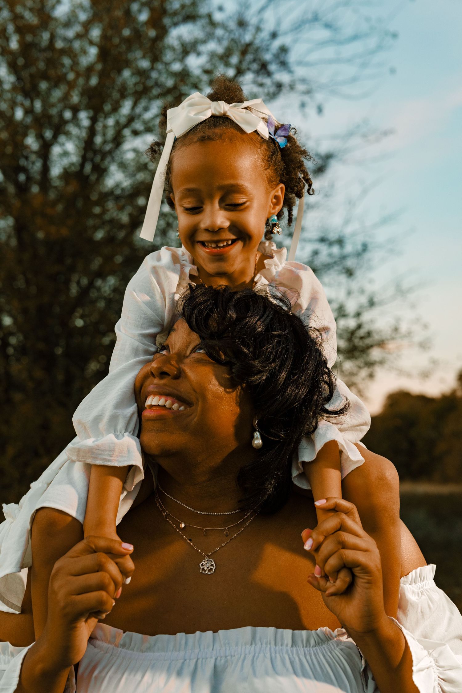 A joyful outdoor portrait featuring a tender piggyback ride moment against a sunset sky.