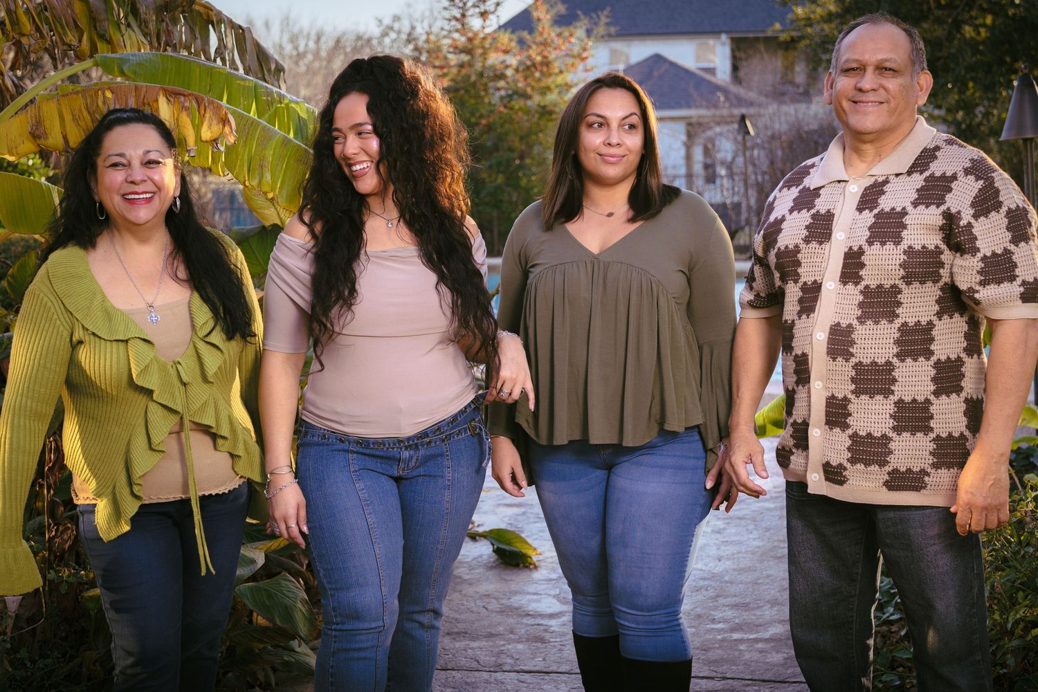 Group portrait of four people dressed casually outdoors during golden hour.