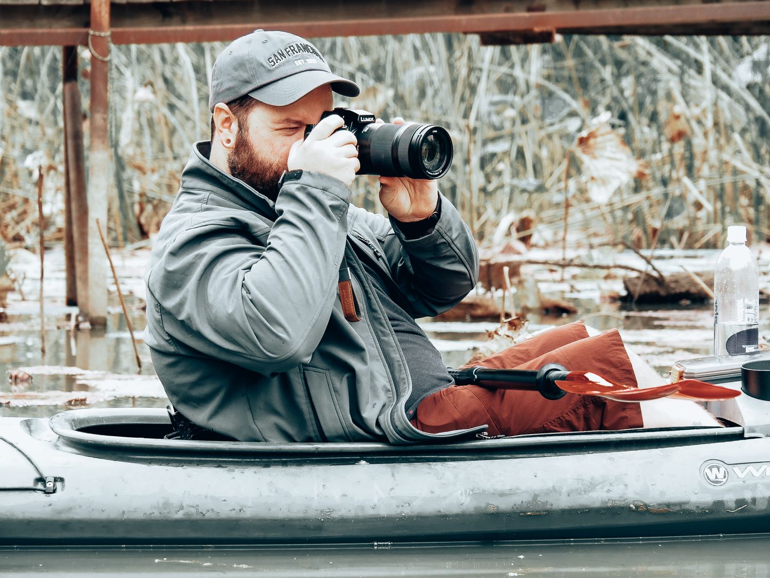 Photographer taking pictures from kayak in wetland area during winter.