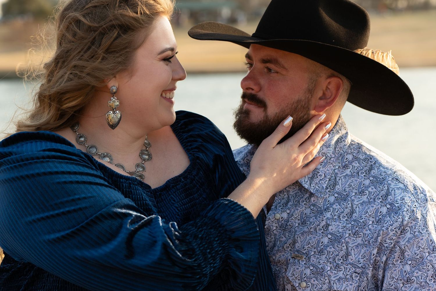 Couple in western wear sharing tender moment during outdoor photoshoot.