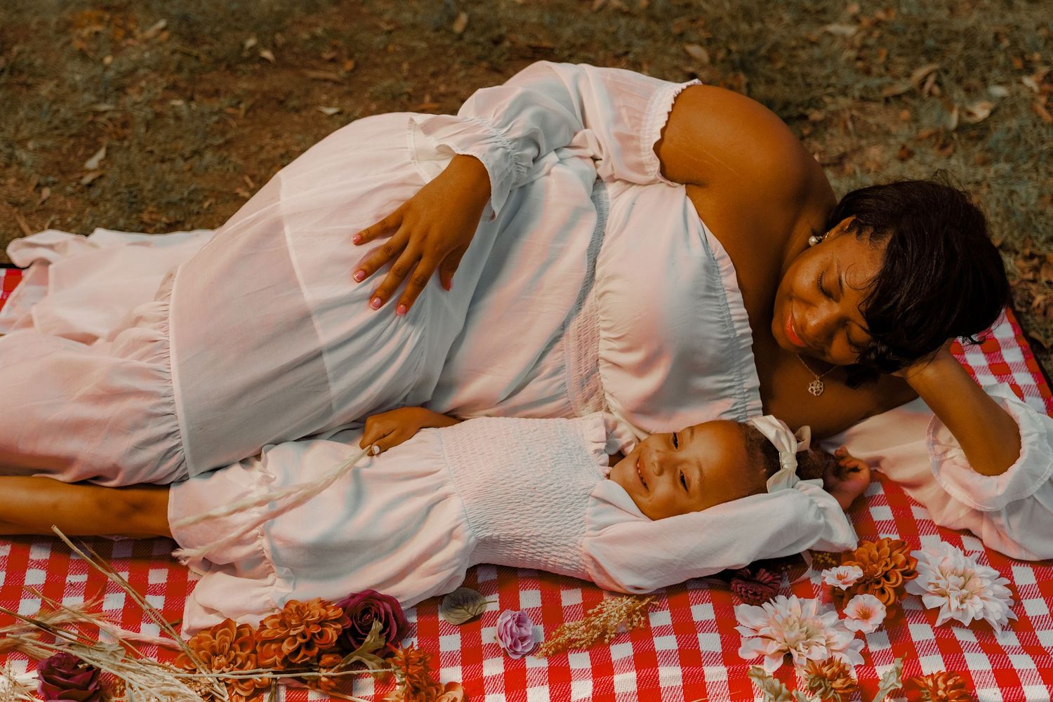 A tender moment between parent and child resting on a red checkered picnic blanket.