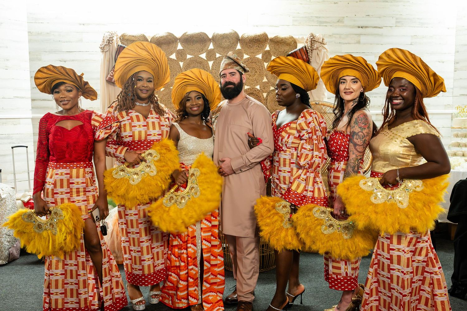 Wedding party members wear matching orange and red patterned outfits with yellow accessories.