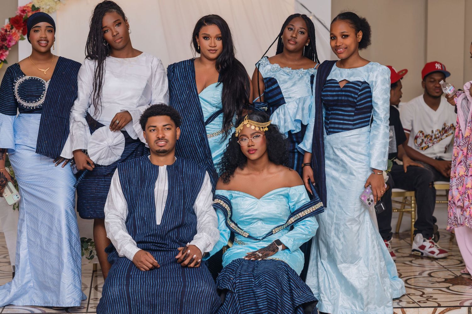 A group wearing coordinated blue and white formal attire poses together for a celebratory photoshoot.