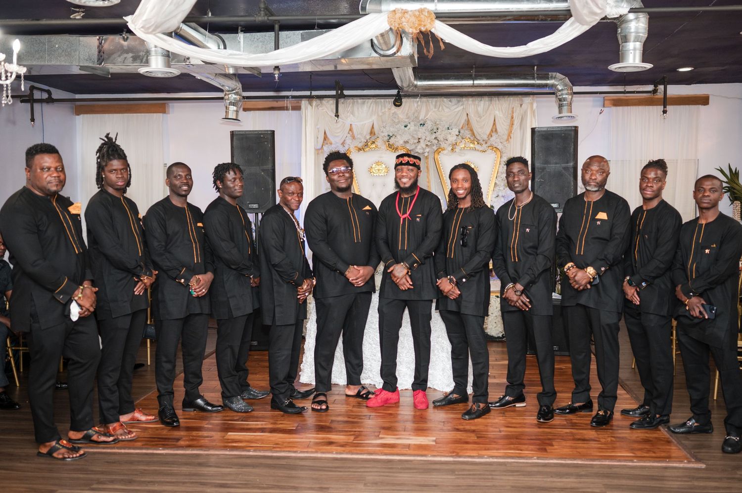 Groomsmen in black suits pose together at an elegant indoor wedding venue.