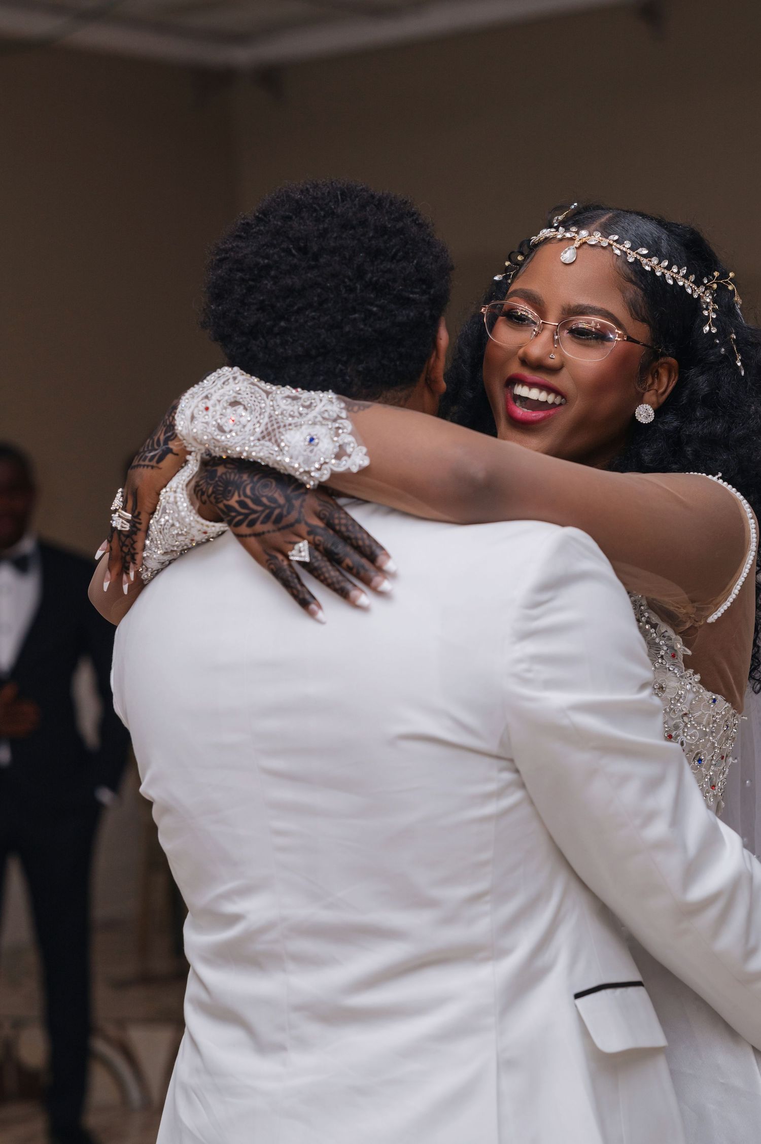 A joyful embrace at a wedding celebration shows the bride wearing a sparkly headpiece and white gown.