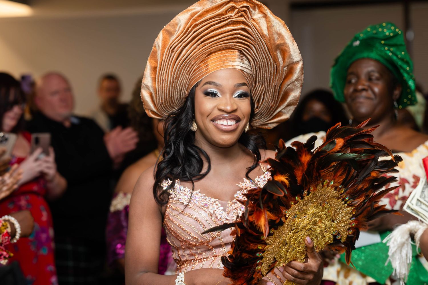 Celebration featuring traditional Nigerian attire with copper gele and decorative fan.