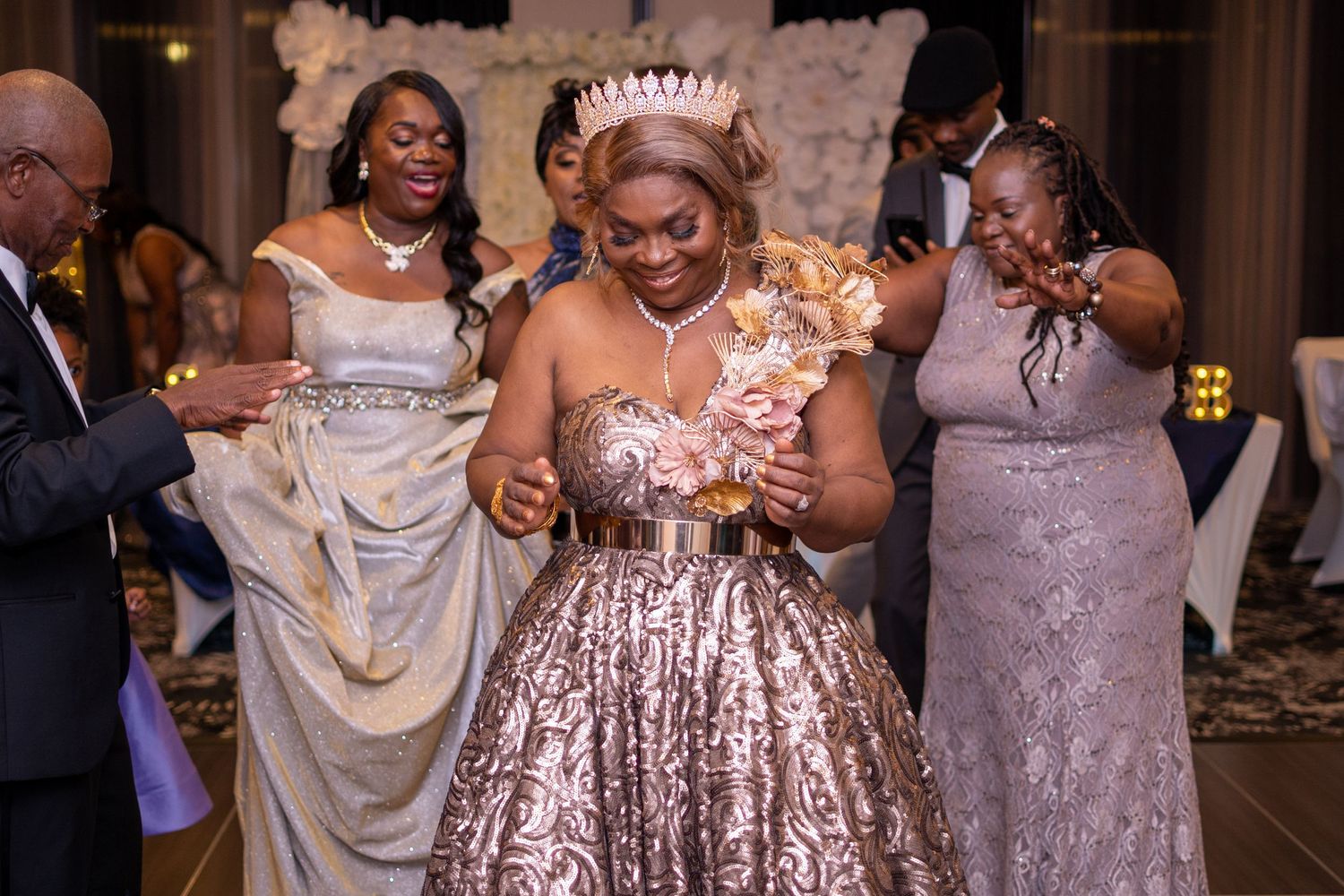 Guests dancing together in formal attire at an elegant reception with white decor.