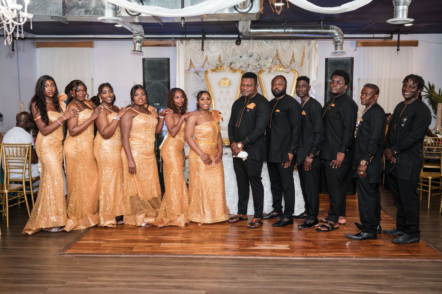 Wedding party lined up with bridesmaids in peach dresses and groomsmen in black suits.