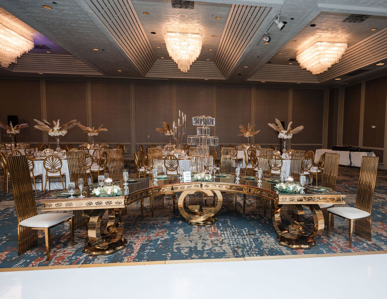 Elegant banquet hall decorated with crystal chandeliers and gold-accented tables arranged for a formal wedding reception.