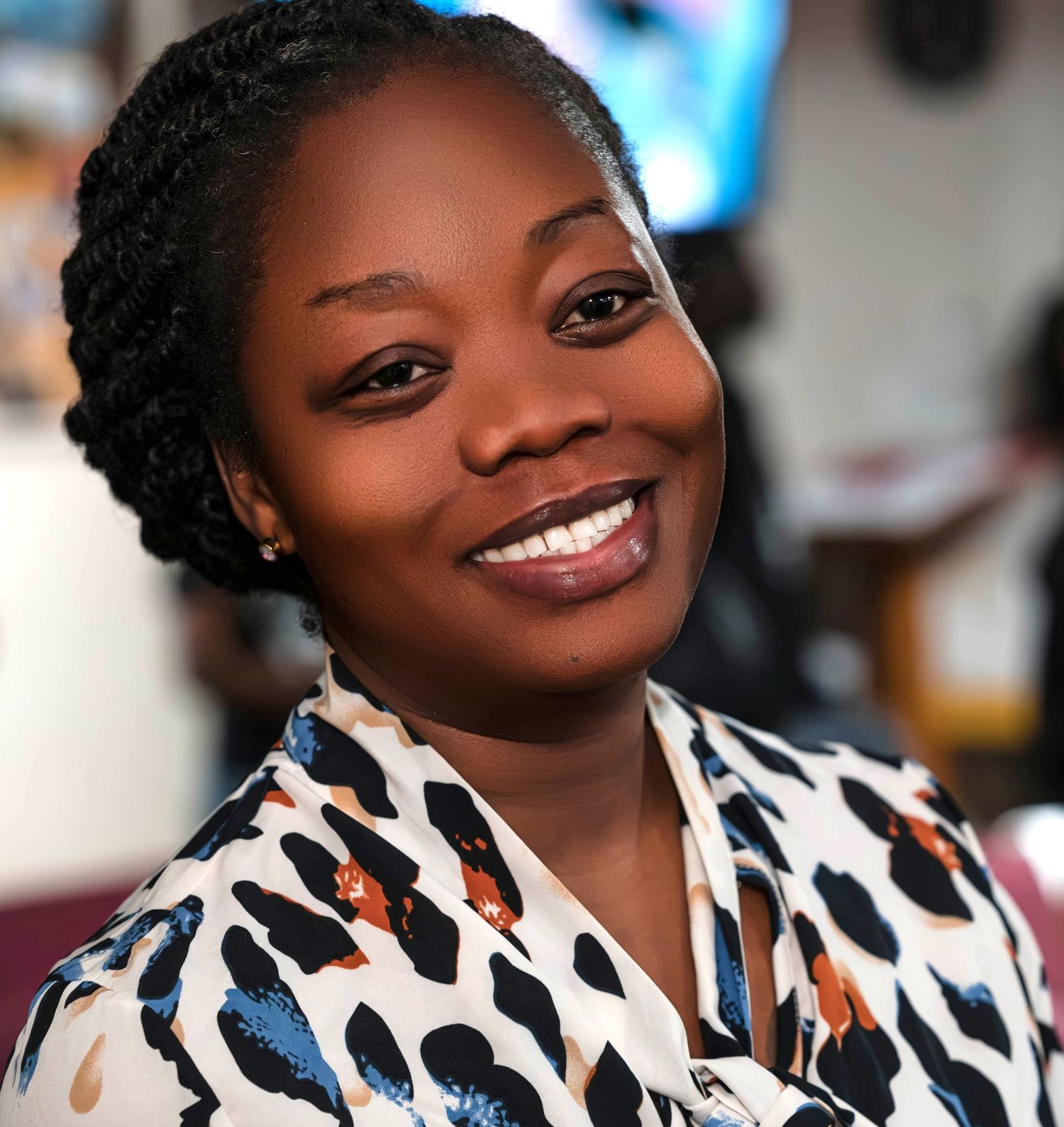 Woman wearing a stylish black and white patterned blouse smiles warmly at the camera.