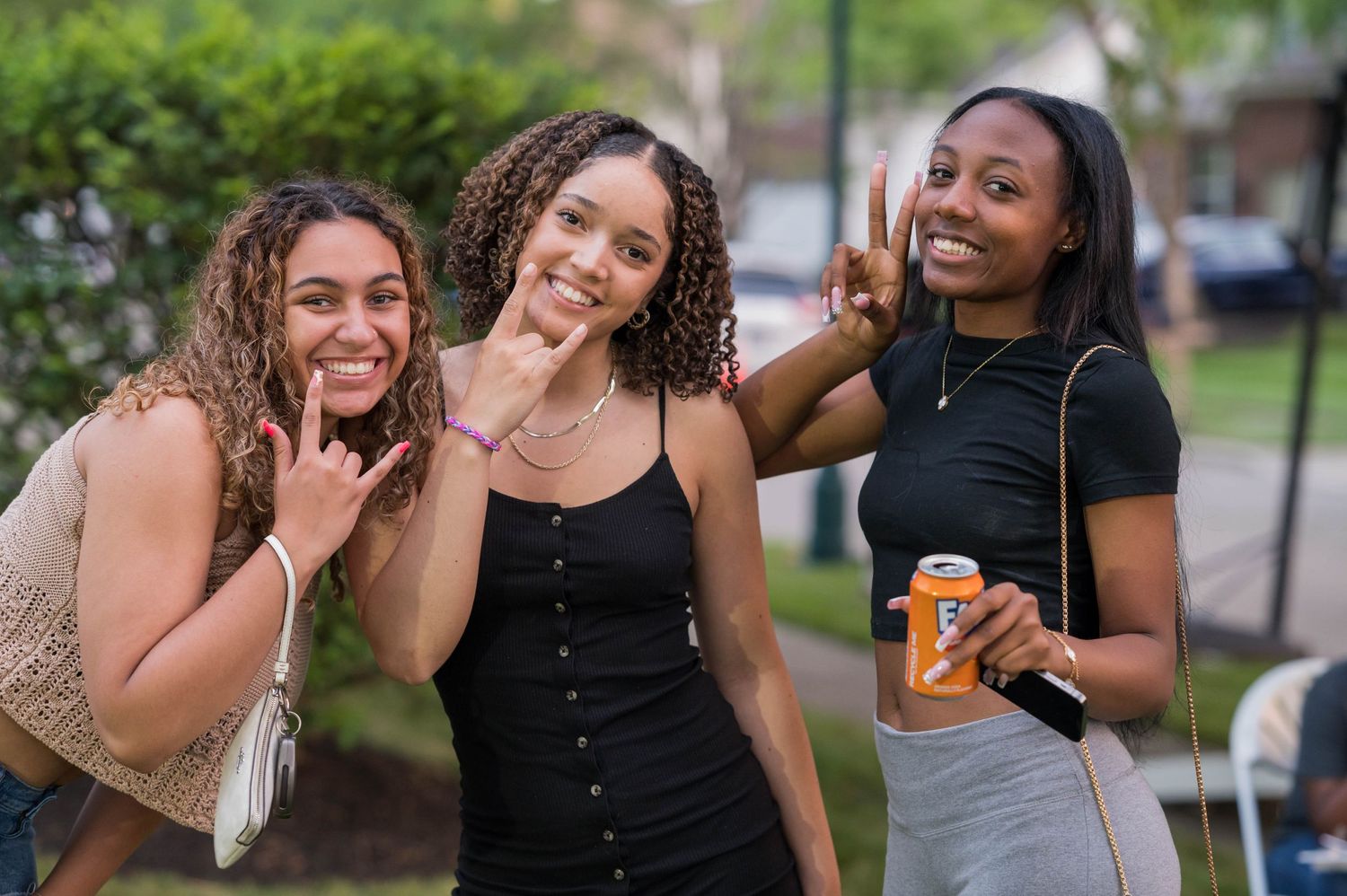 Three friends pose playfully at an outdoor social gathering.