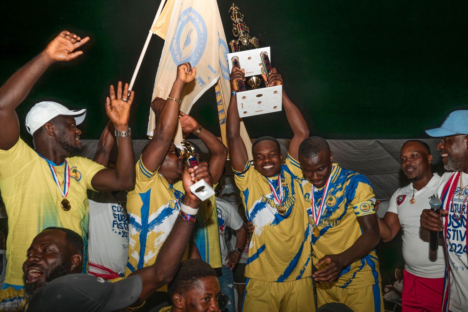 Soccer team celebrates with trophy and medals after championship victory.