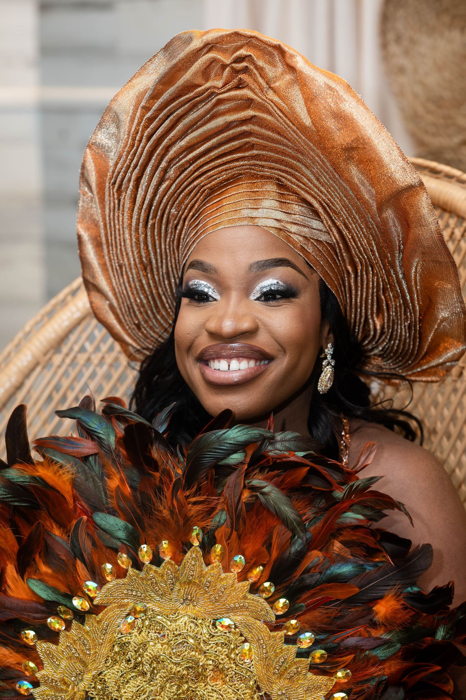 Wedding look featuring copper gele headwrap and feathered fan accessories.