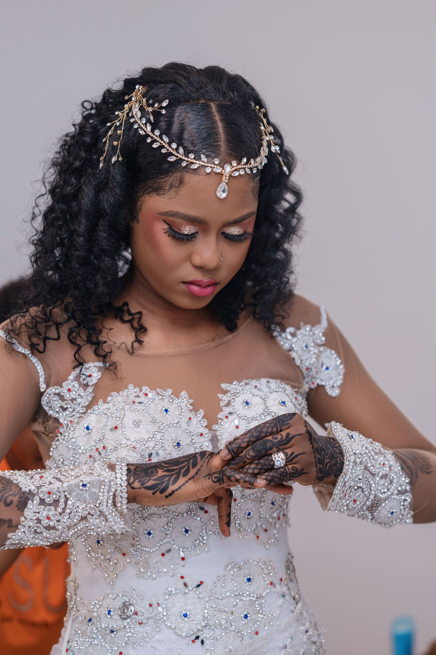 An elegant bridal portrait showcasing intricate white lace details and a delicate crystal headpiece against a neutral background.