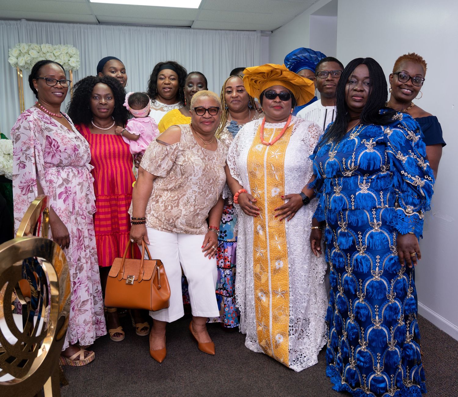 A group of women in colorful traditional African dresses and headwraps pose together at an event.
