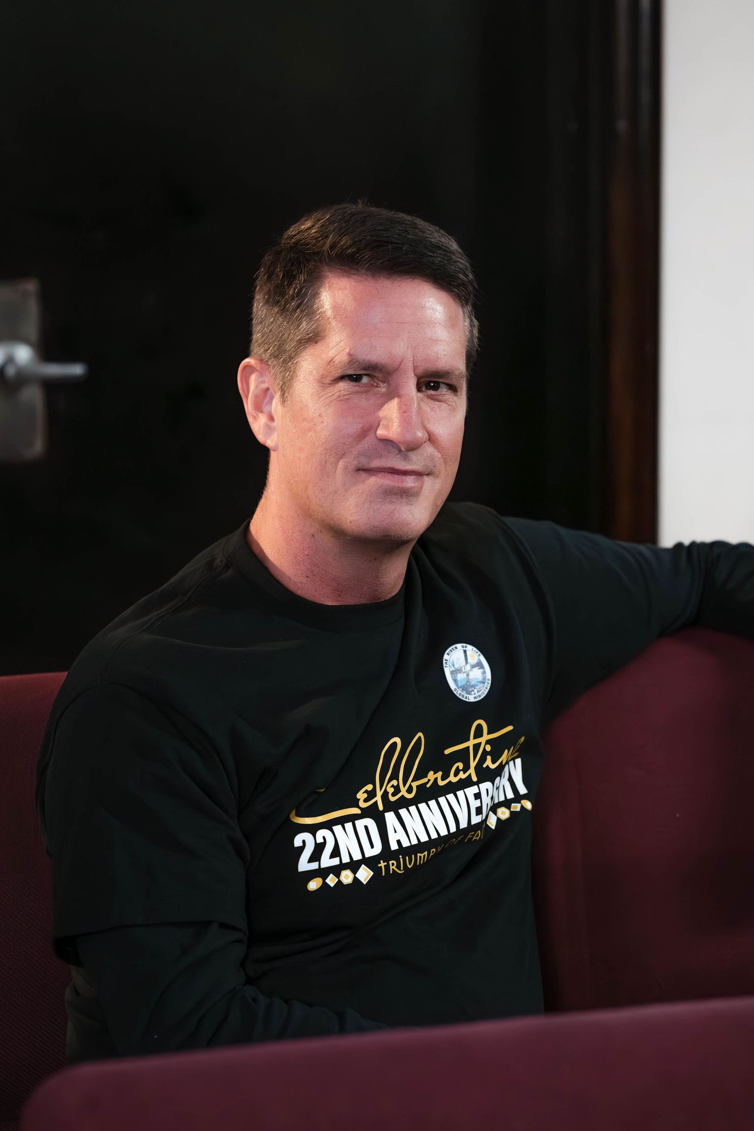 Person wearing black t-shirt with 22nd anniversary text sitting in theater seat.