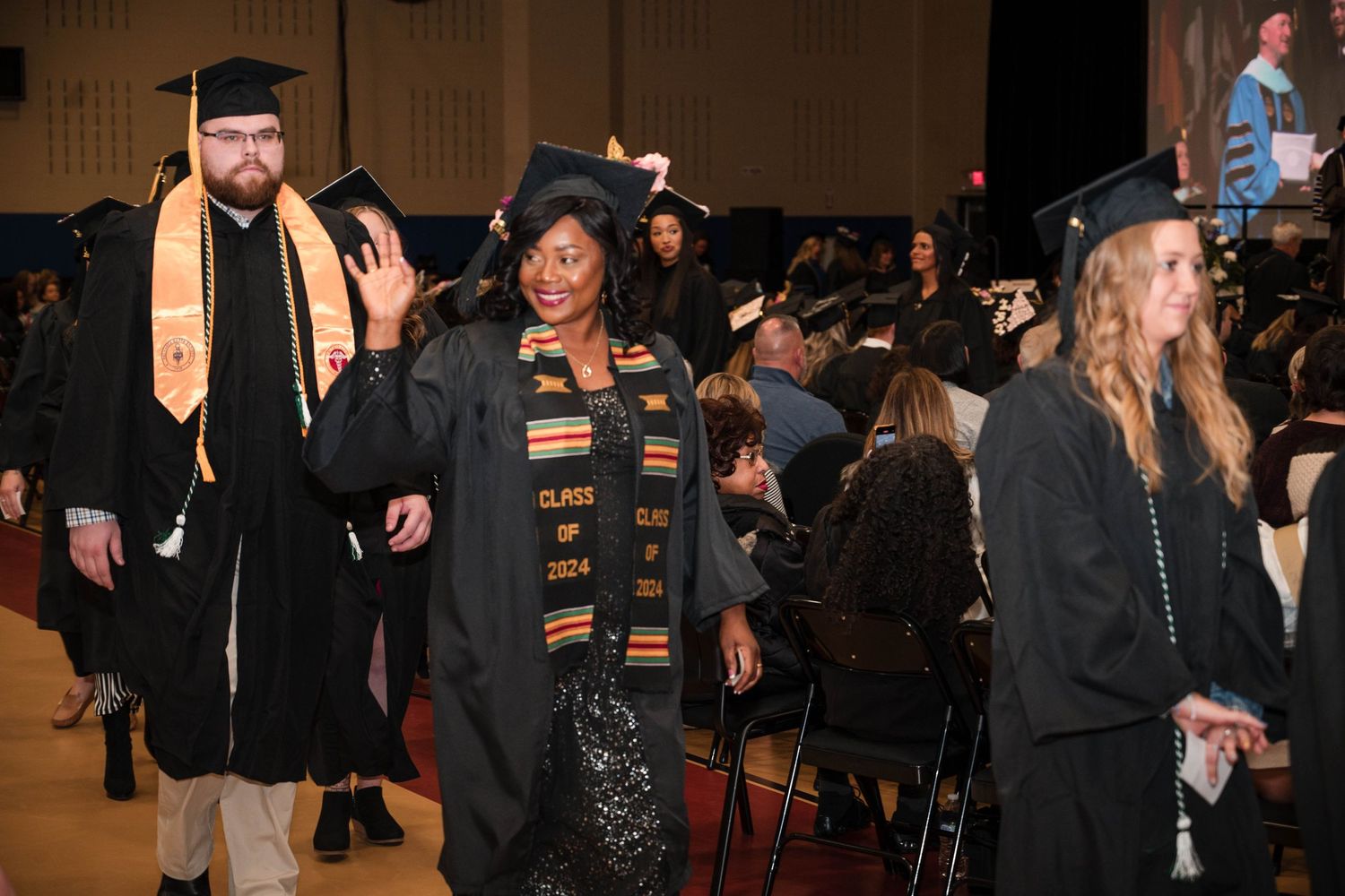Graduates in academic regalia and stoles process during a graduation ceremony.
