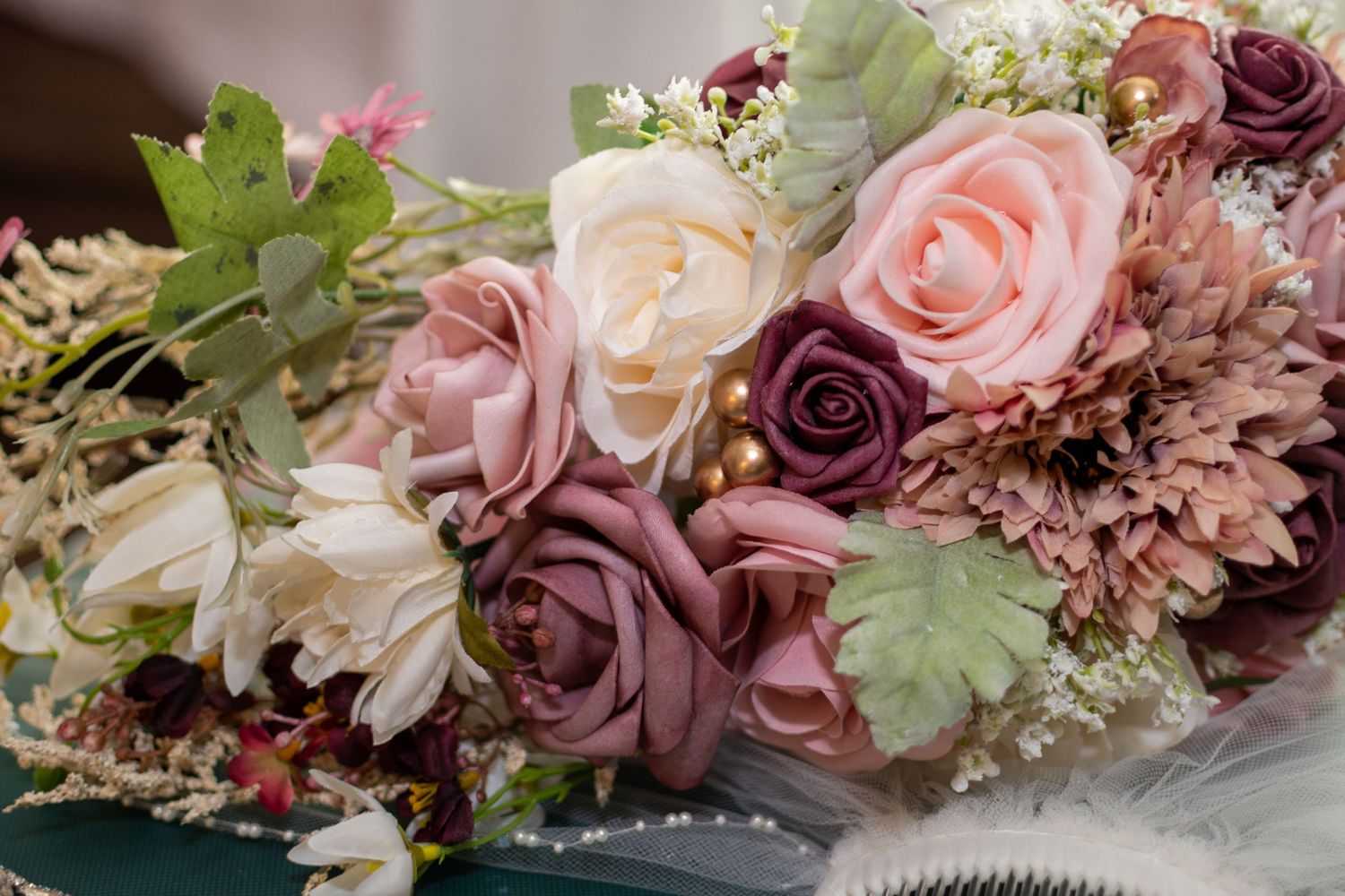 Beautiful wedding bouquet with pink, mauve and cream roses mixed with delicate greenery and other florals.
