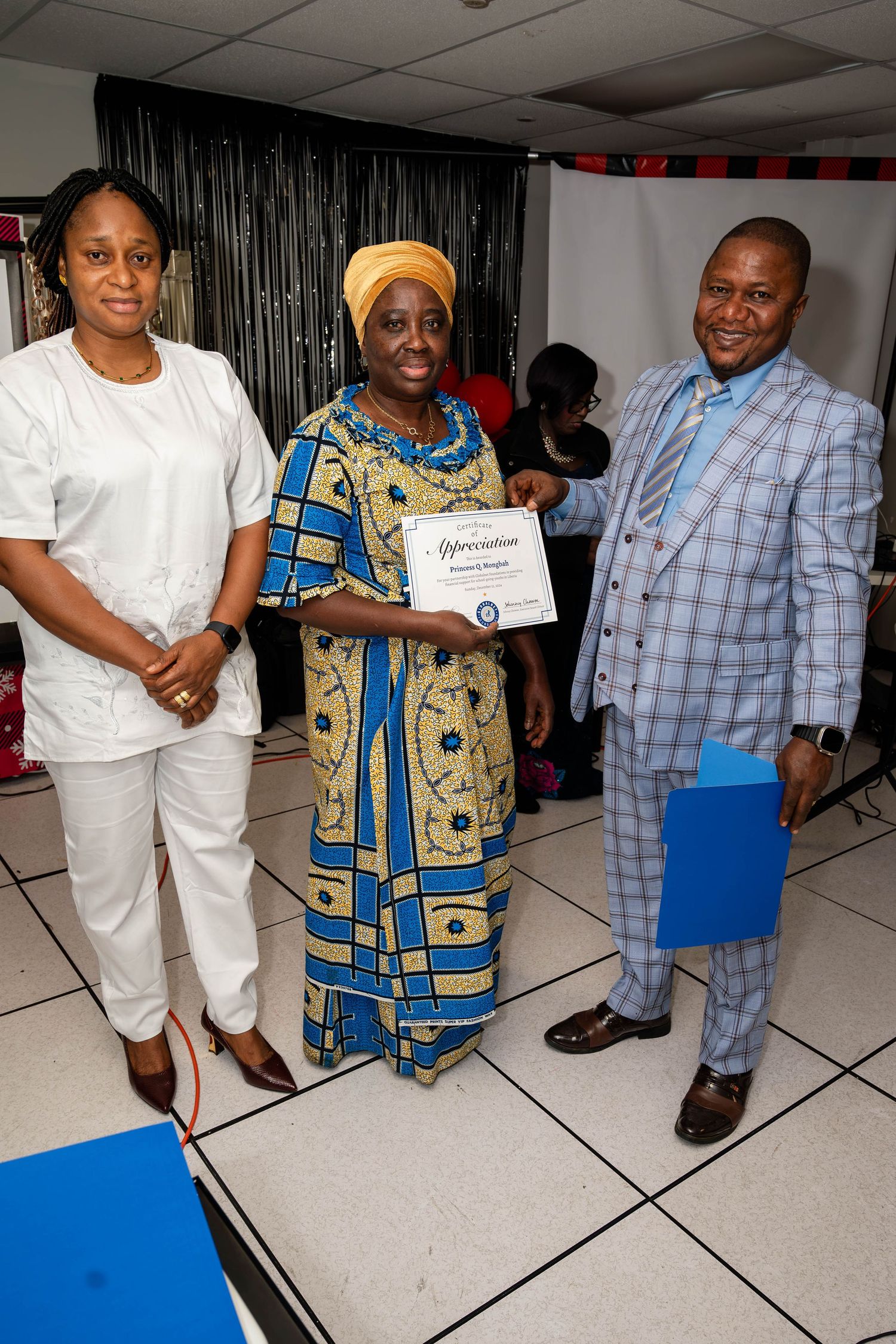 Three people stand together posing with a certificate at an awards ceremony.