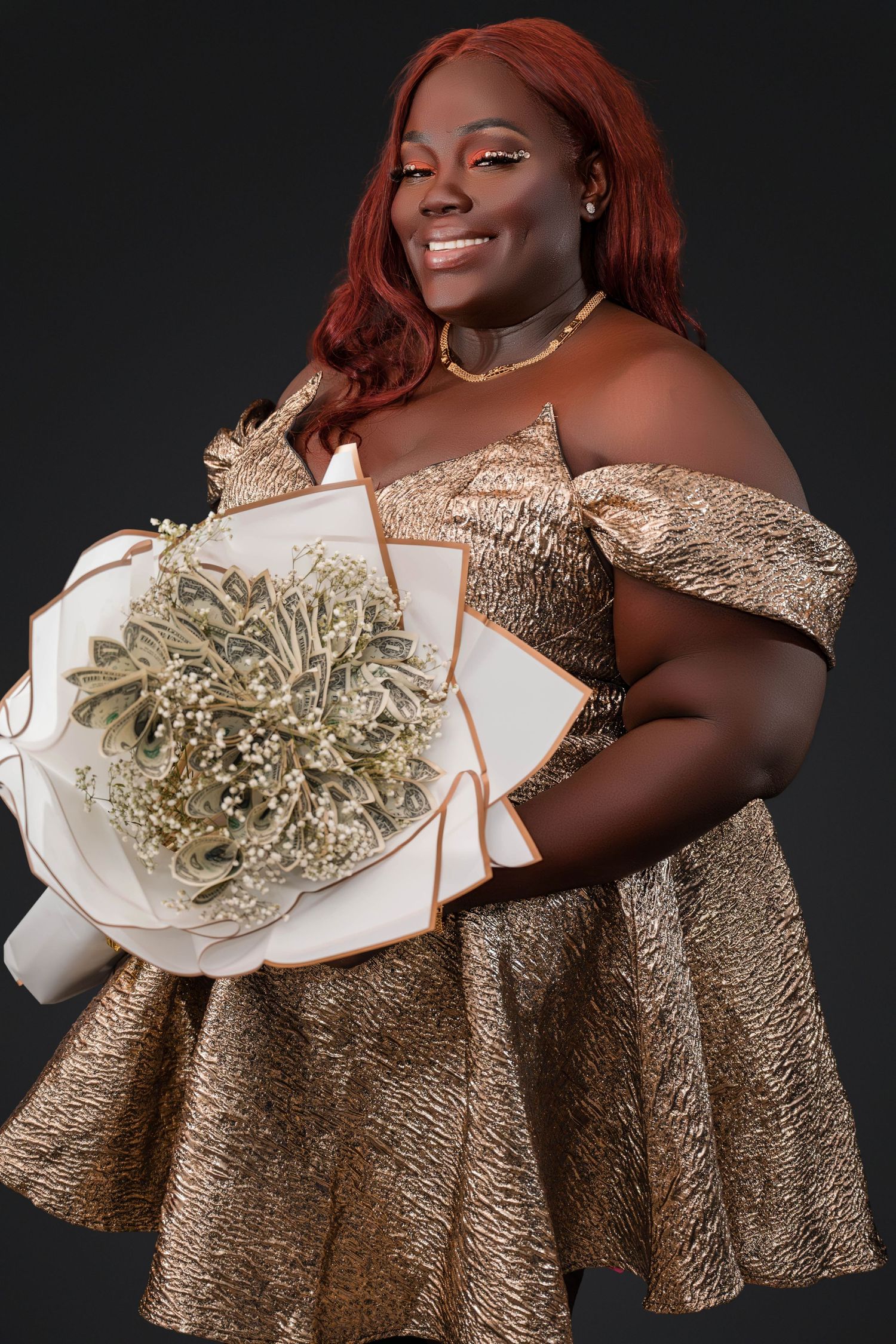 A person in a shimmering gold off-shoulder dress poses with a sparkly white bouquet against a dark background.