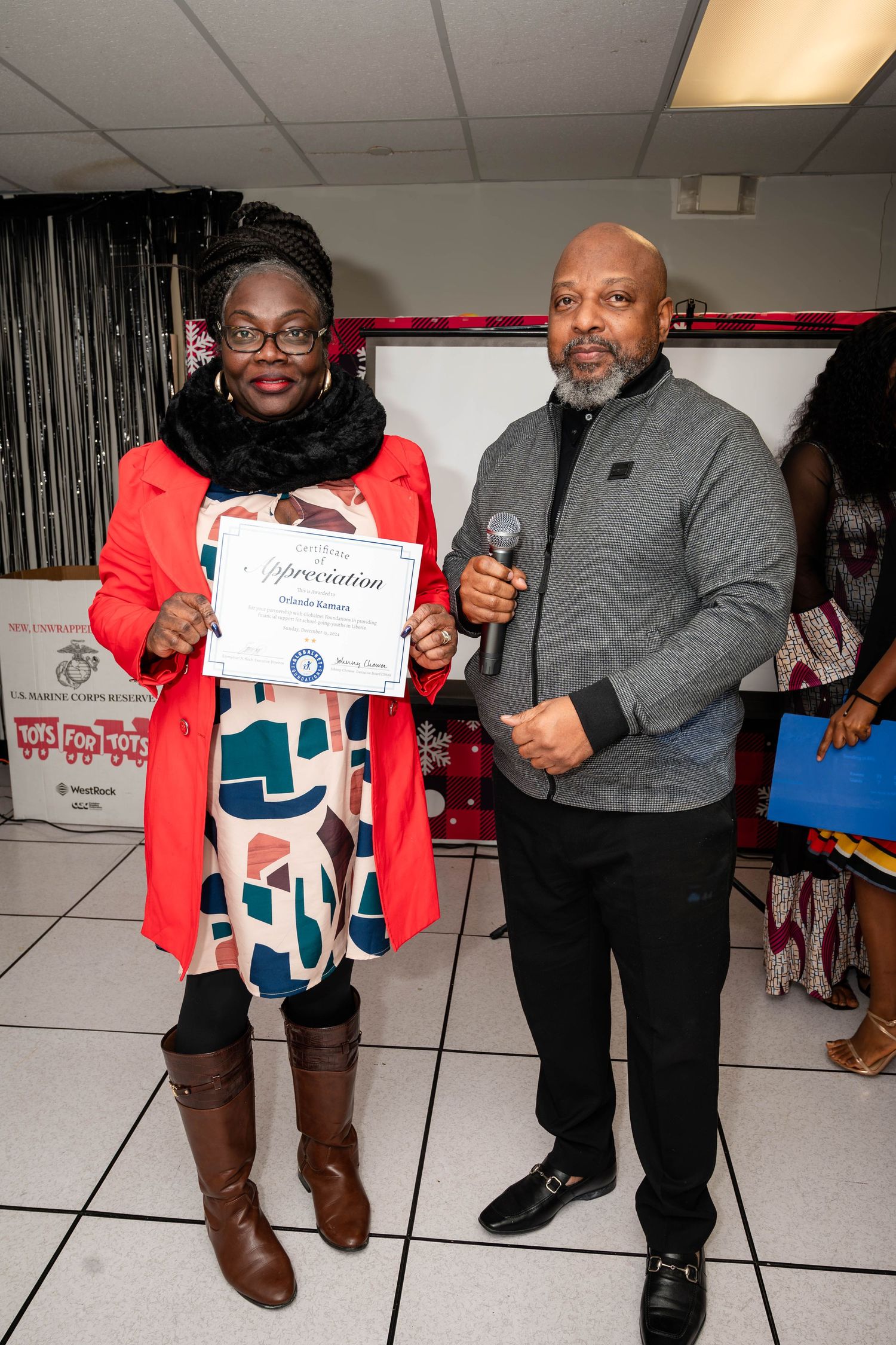 Two people pose with a certificate during an awards ceremony.