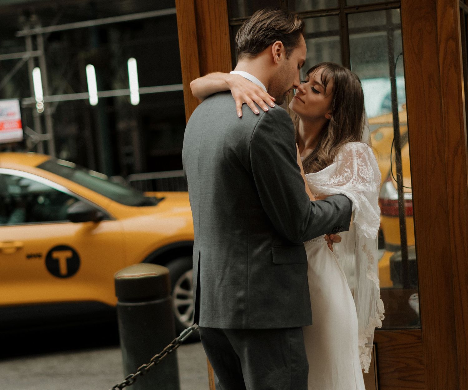A romantic couple embraces and kisses on a New York City street with a yellow taxi cab visible in the background.